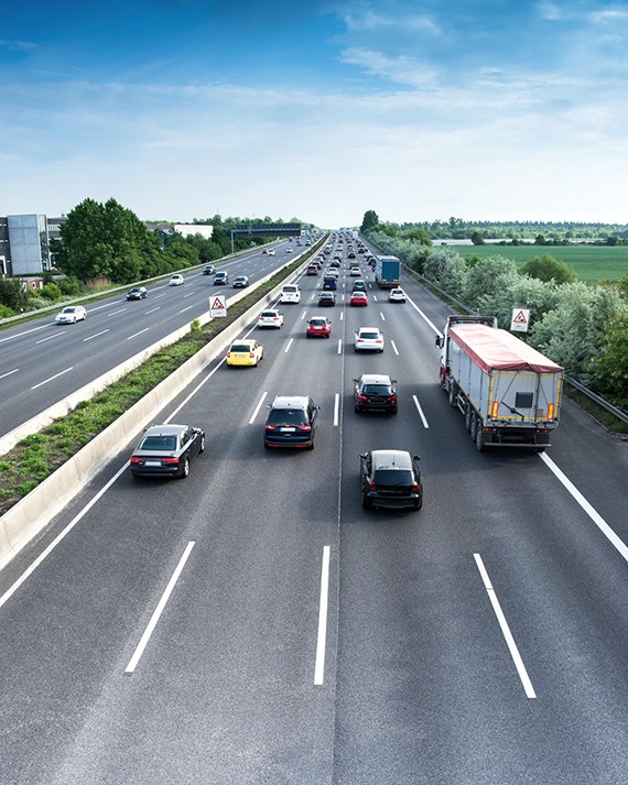Traffic on a widened interstate beside a tall roadside noise wall